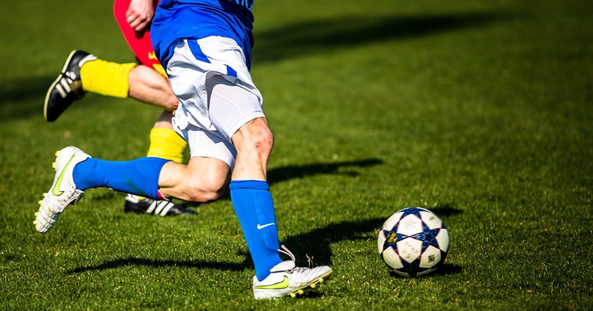 Gambe di calciatori che calciano un pallone sul campo