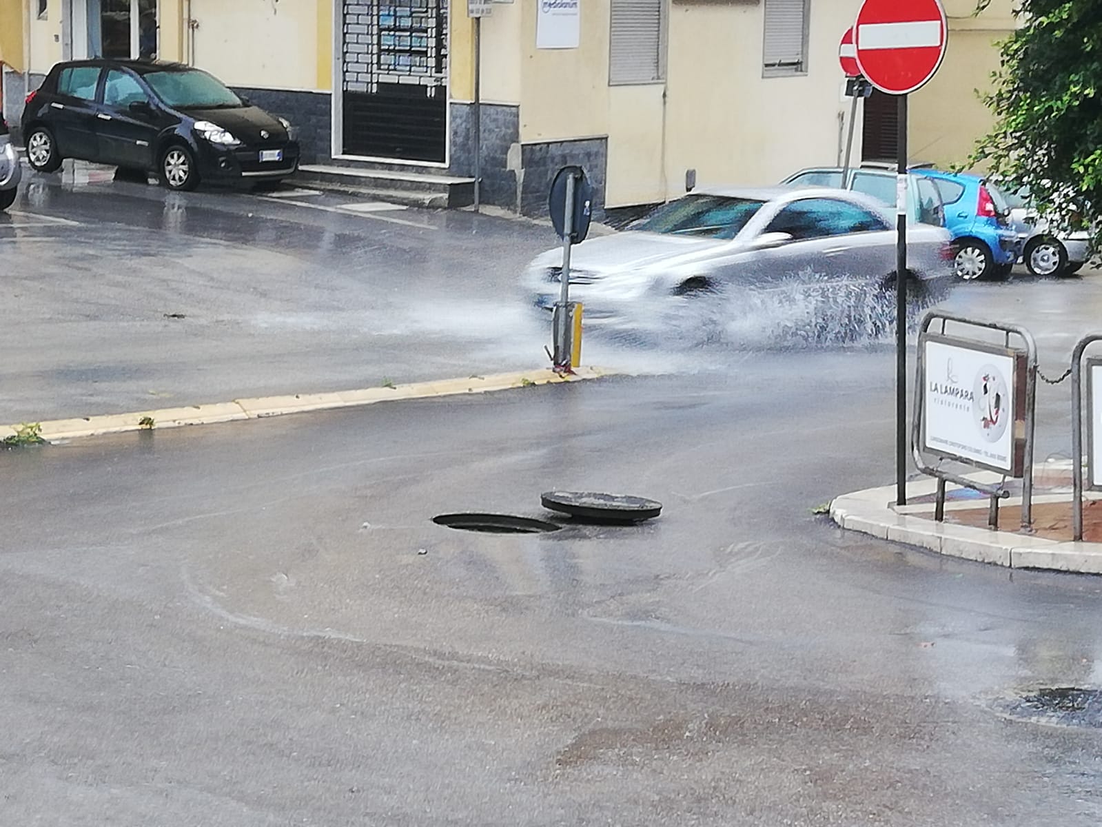 Salta il coperchio di un tombino mentre piove, due giovani prontamente lo rimettono (video)