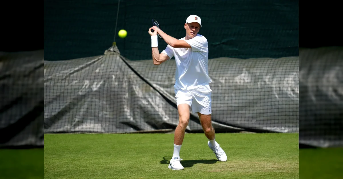 Jannik Sinner colpisce di dritto sull'erba di Wimbledon, con la racchetta alzata e lo sfondo del Centre Court
