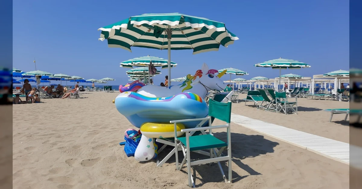 Borsa frigo con panini e bibite sulla spiaggia, davanti a un cartello di divieto