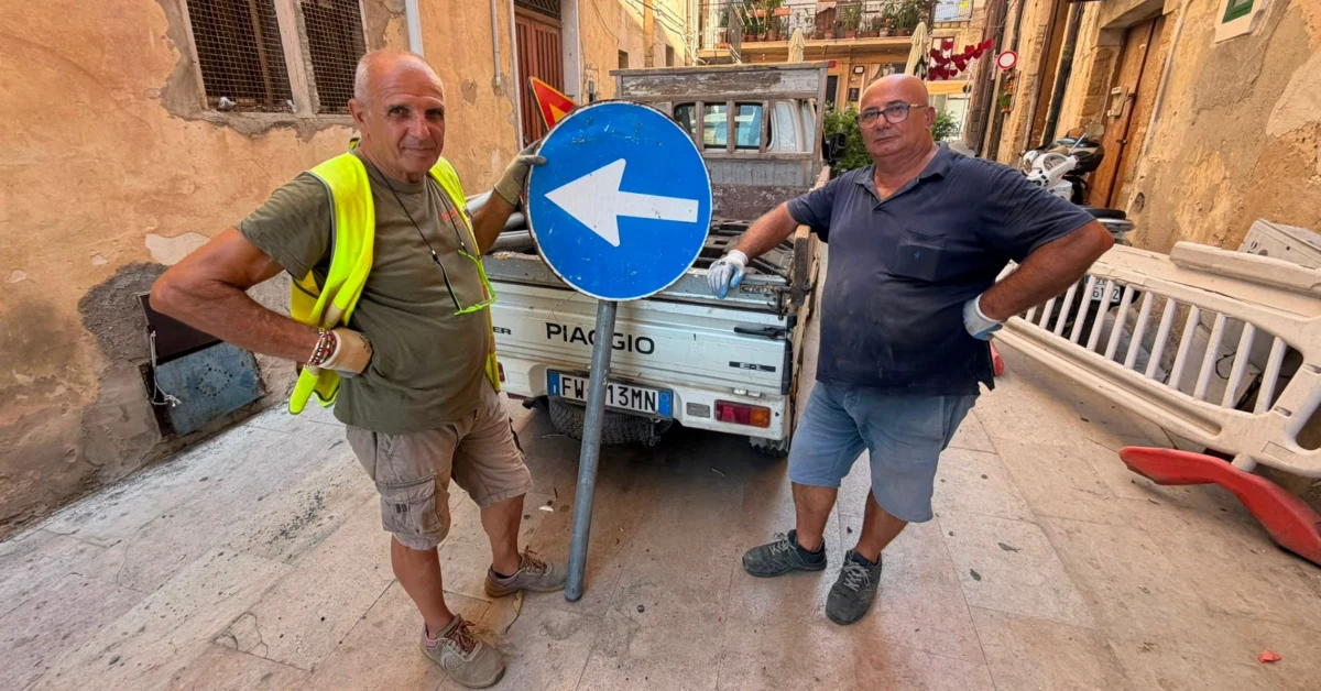 Due operai comunali della segnaletica di Sciacca con transenne e segnali stradali
