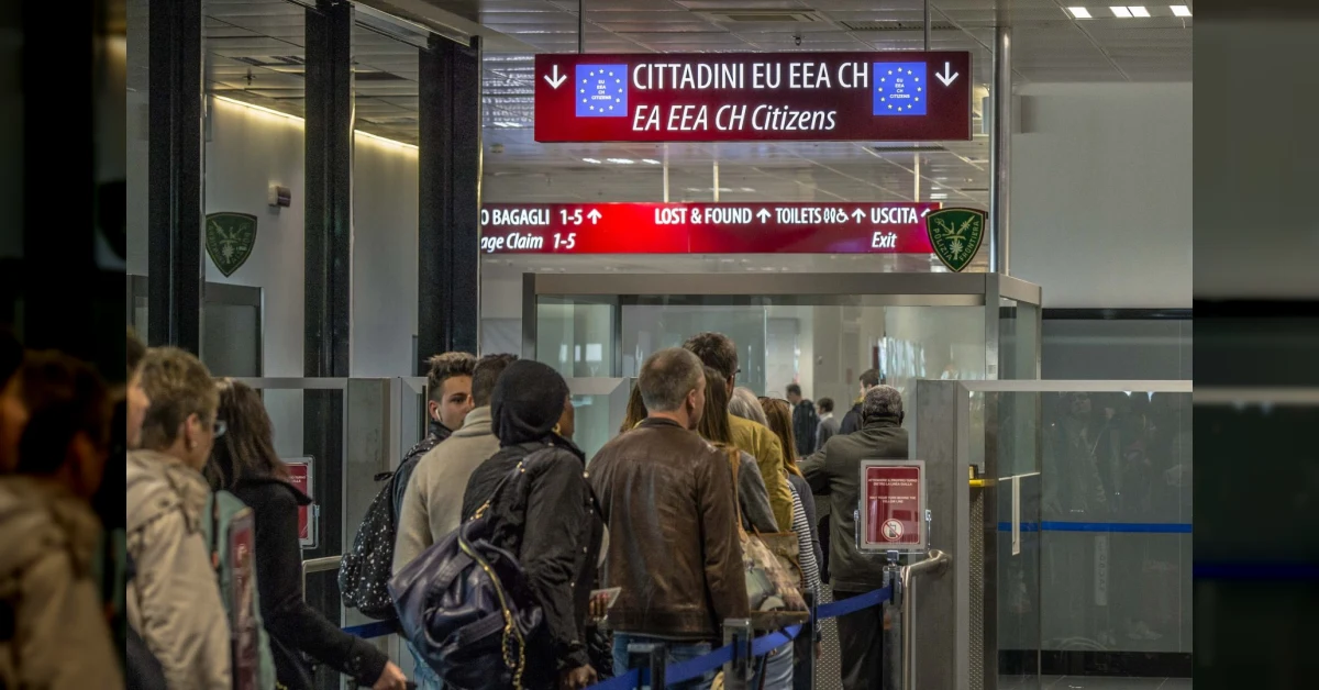 Controlli di frontiera in aeroporto con agenti e viaggiatori, tema della reintroduzione delle verifiche tra Spagna e Italia