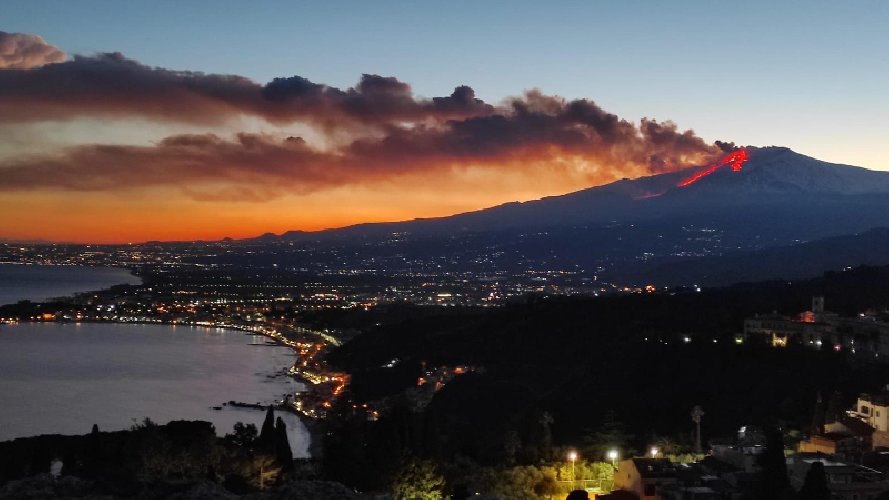 Cratere Voragine dell'Etna in eruzione con colonna di cenere e bagliore notturno