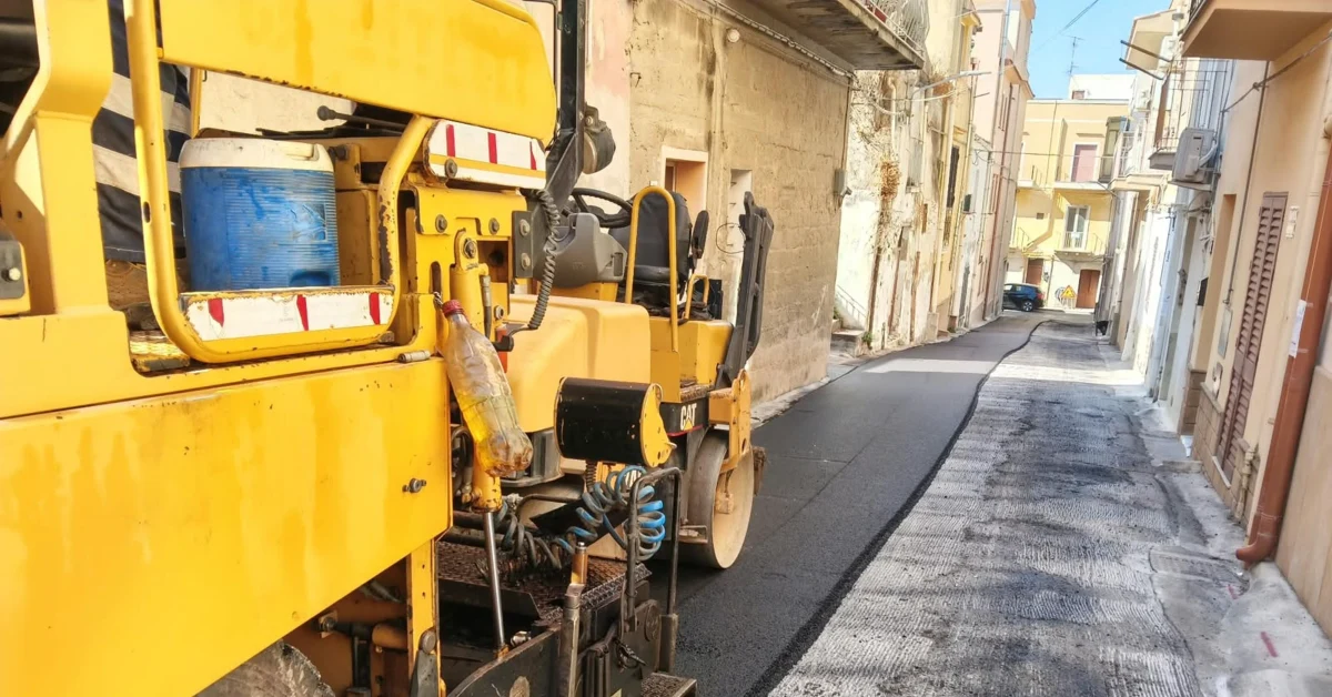 Lavori di asfaltatura sulla salita San Michele con mezzi da cantiere e operai impegnati nella posa del nuovo manto stradale