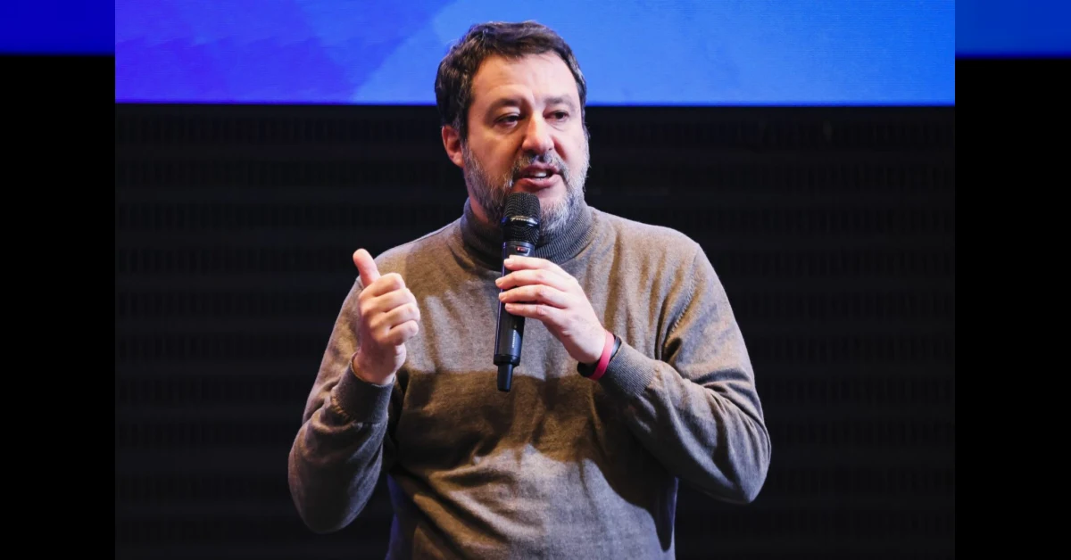 Matteo Salvini in un'intervista sul palco accanto a bandiere italiane ed europee, simbolo del negoziato sulle sanzioni alle imprese in Russia