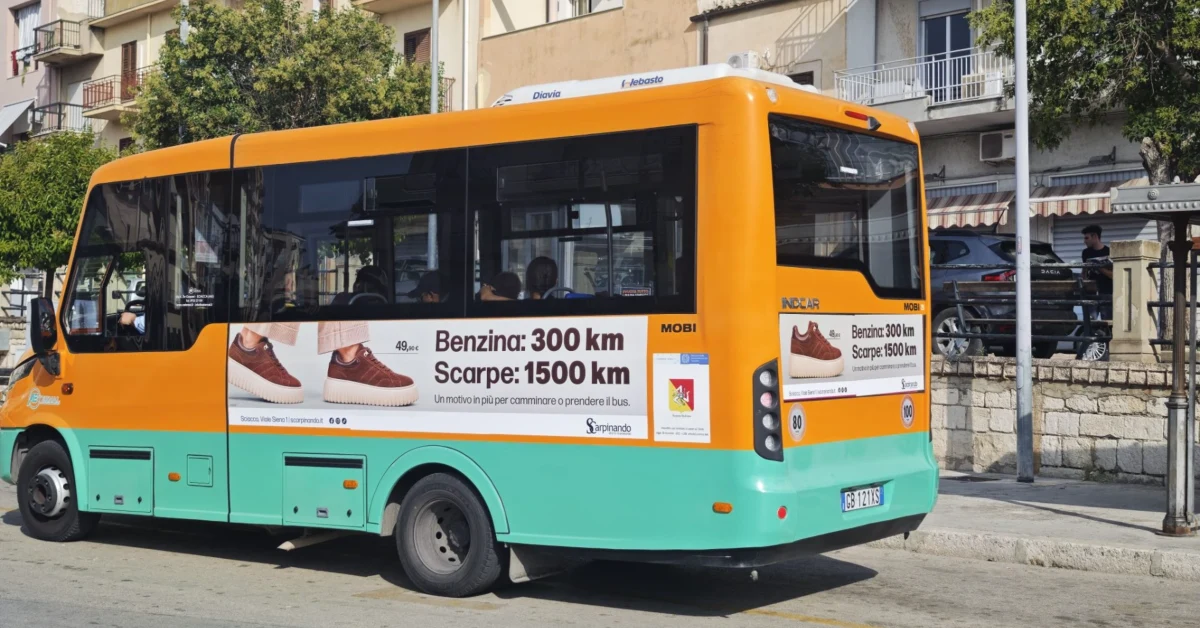 Autobus urbano di Sciacca con la campagna pubblicitaria di Scarpinando che confronta 300 km in benzina e 1.500 km con un paio di scarpe da 49,90 euro.